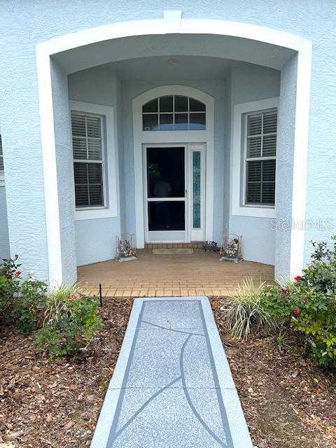 A front entryway features a blue stucco facade, a screened door, and a paved walkway — 11752 WAYSIDE WILLOW COURT, HUDSON, FL