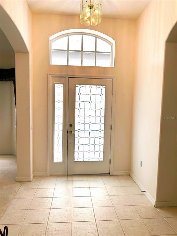 An entryway features a white front door with a glass insert, tile flooring, and arched window — 11752 WAYSIDE WILLOW COURT, HUDSON, FL