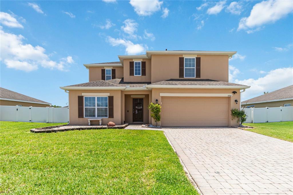 A two-story tan stucco house with a two-car garage and a paved driveway — 3707 BRAMBLY AVENUE, ST CLOUD, FL