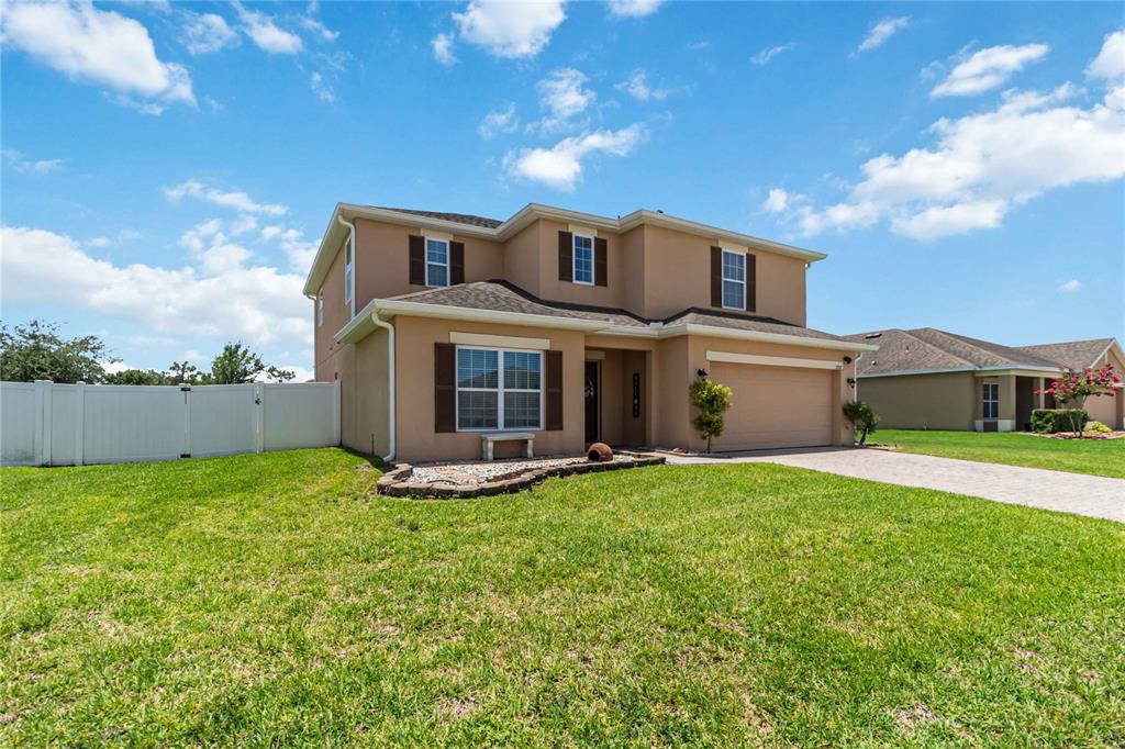 A two-story tan house with a two-car garage and a white vinyl fence — 3707 BRAMBLY AVENUE, ST CLOUD, FL