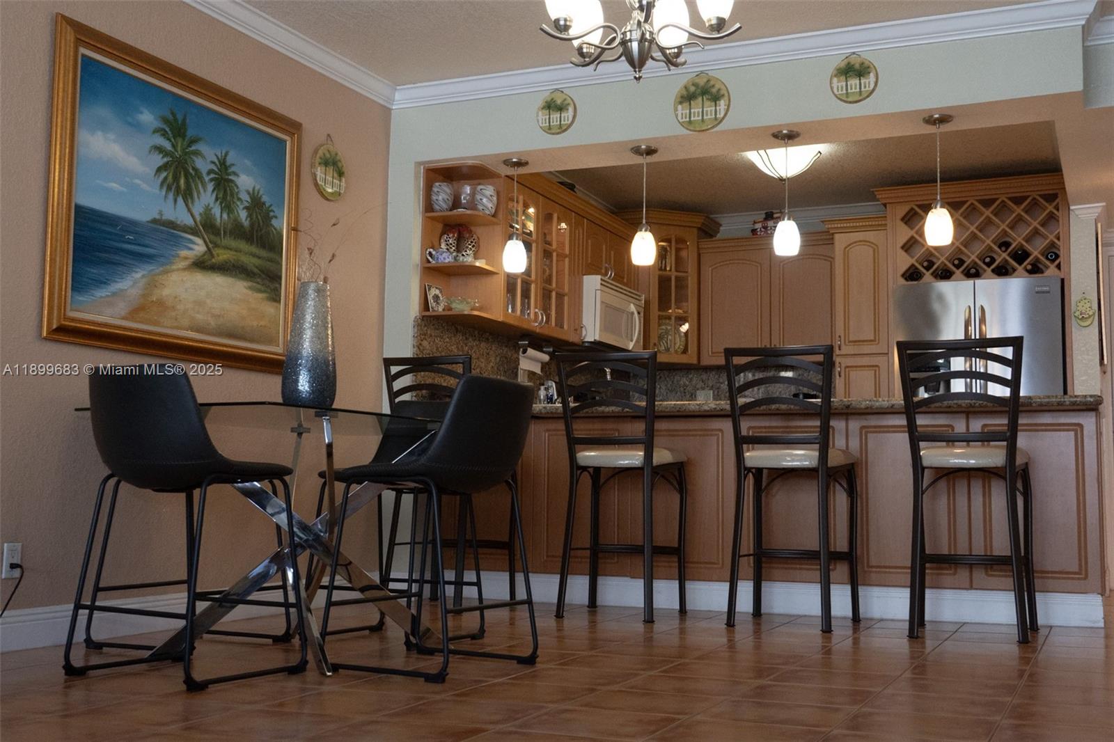 A kitchen with wood cabinets and a breakfast bar sits adjacent to a dining area — 3725 S Ocean Dr # 1021, Hollywood FL 33019, HOLLYWOOD, FL