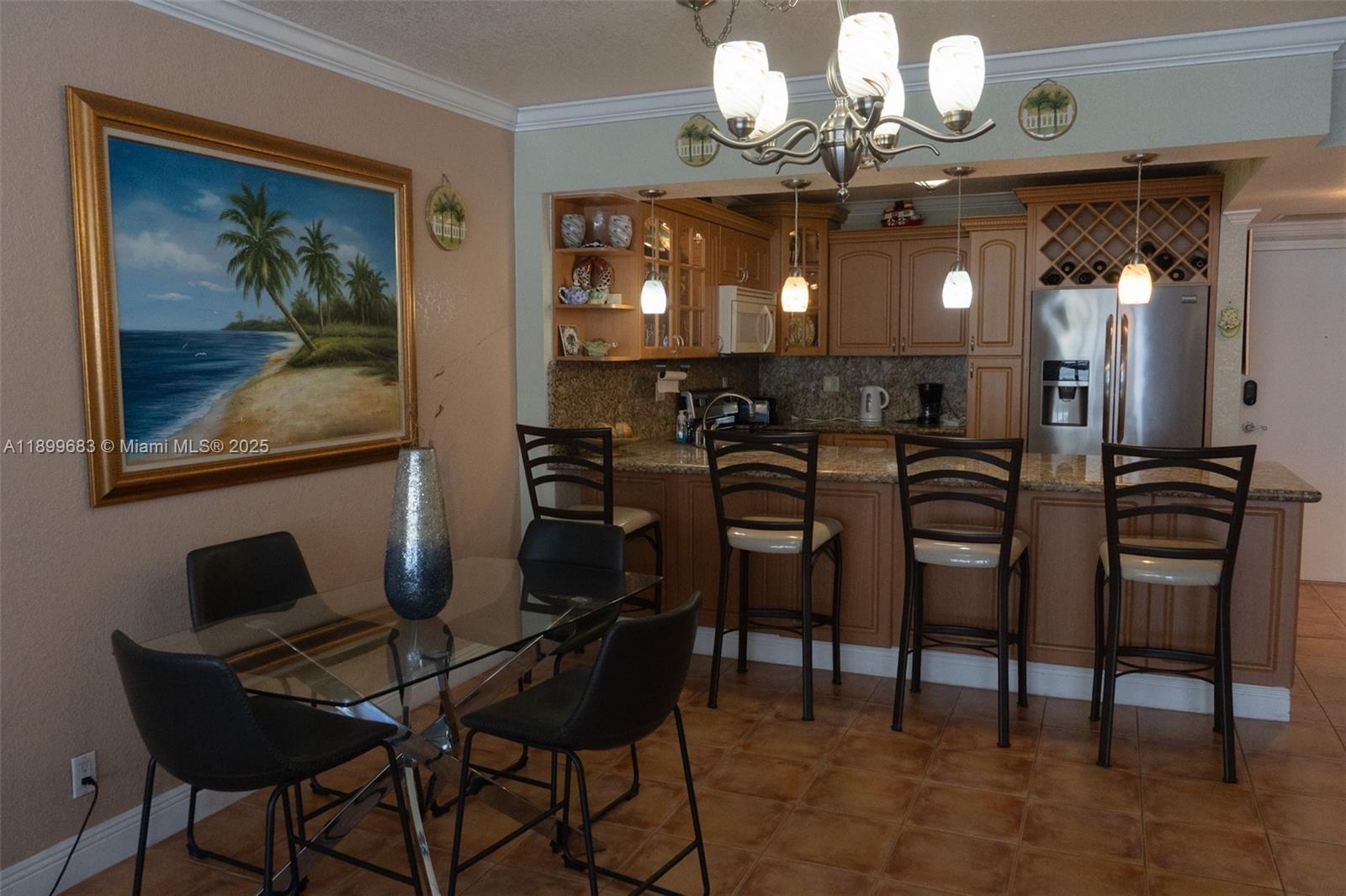 A dining area with a glass table and bar seating adjacent to a kitchen — 3725 S Ocean Dr # 1021, Hollywood FL 33019, HOLLYWOOD, FL