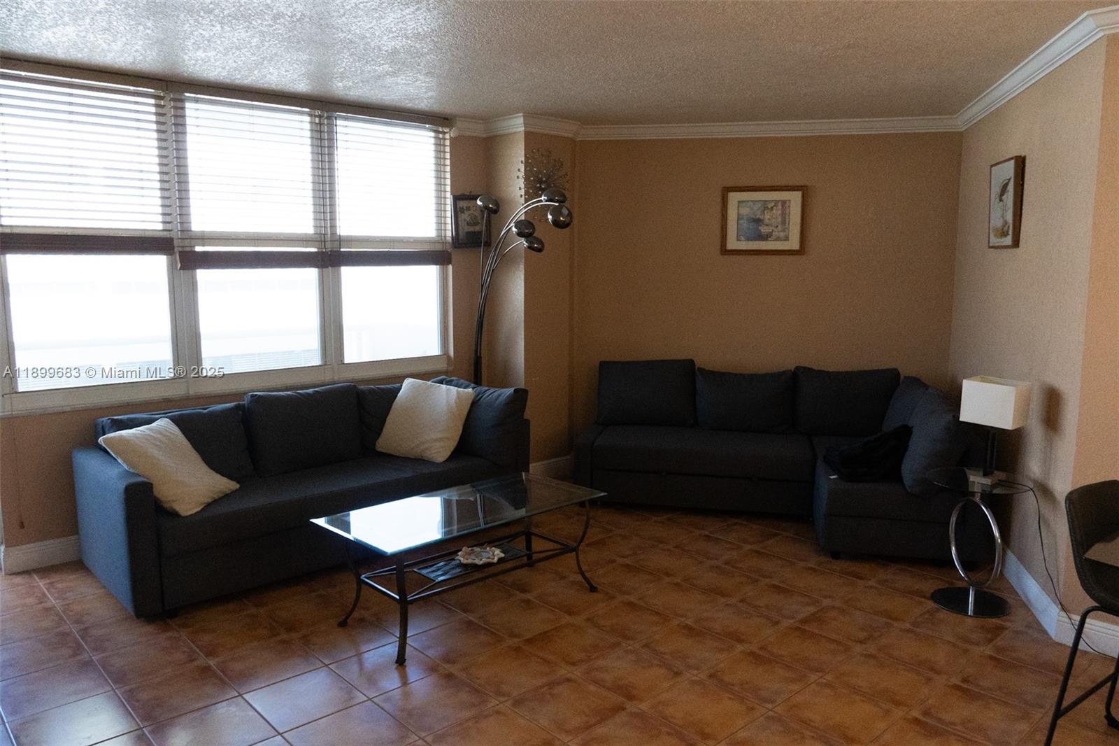 A living room features two dark sofas, a glass coffee table, and tile flooring — 3725 S Ocean Dr # 1021, Hollywood FL 33019, HOLLYWOOD, FL