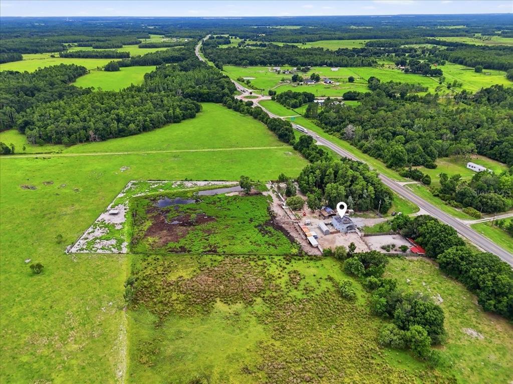 An aerial view shows a house and outbuildings on a large rural lot with pasture — 14445 COMMONWEALTH AVENUE N, POLK CITY, FL