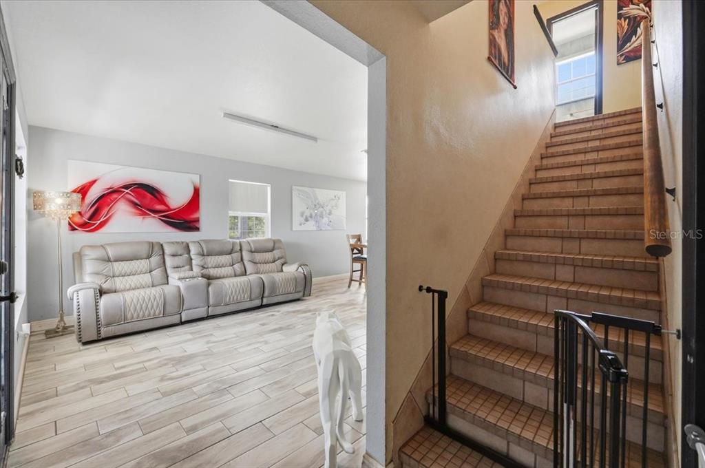 A living room with light wood-look tile floors and a staircase with tiled steps — 14445 COMMONWEALTH AVENUE N, POLK CITY, FL