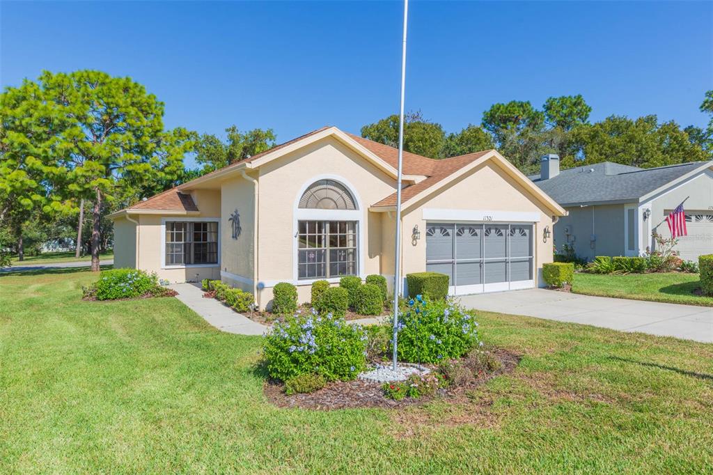 A single-story house with a tan stucco exterior, a garage, and a front yard — 11321 COPLEY COURT, SPRING HILL, FL
