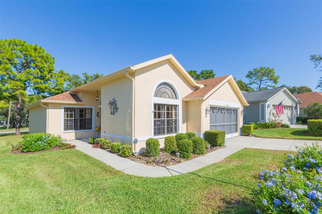A single-story house with a beige stucco exterior, a garage, and a landscaped front yard — 11321 COPLEY COURT, SPRING HILL, FL