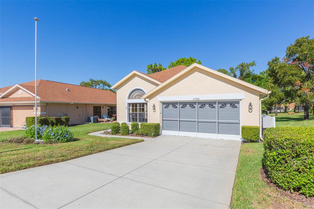 A single-story house with a beige stucco exterior, a screened garage, and a concrete driveway — 11321 COPLEY COURT, SPRING HILL, FL