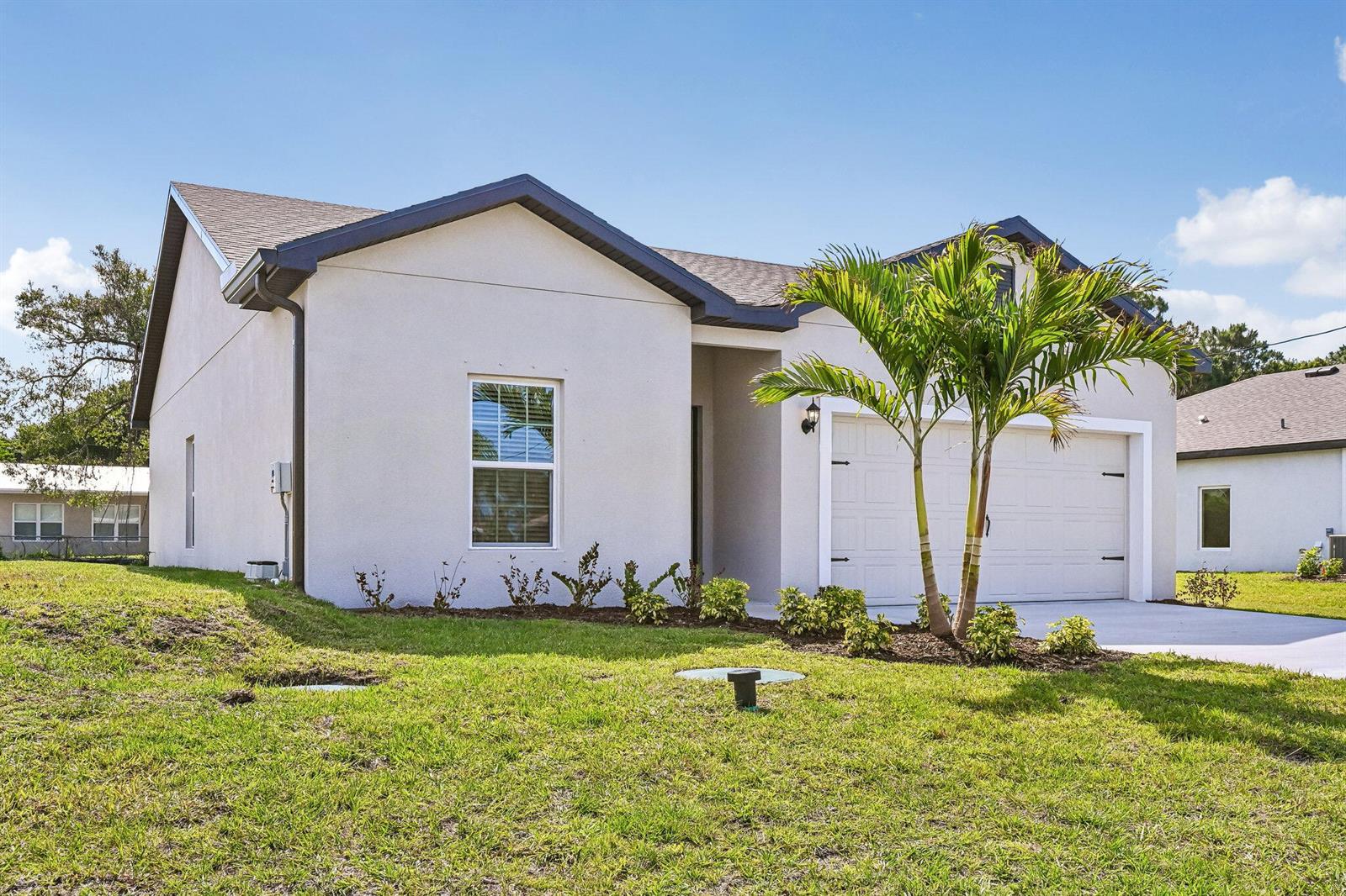 A single-story house with a white stucco exterior, a two-car garage, and a palm tree — 5200 Hickory Drive, Fort Pierce FL 34982, FORT PIERCE, FL