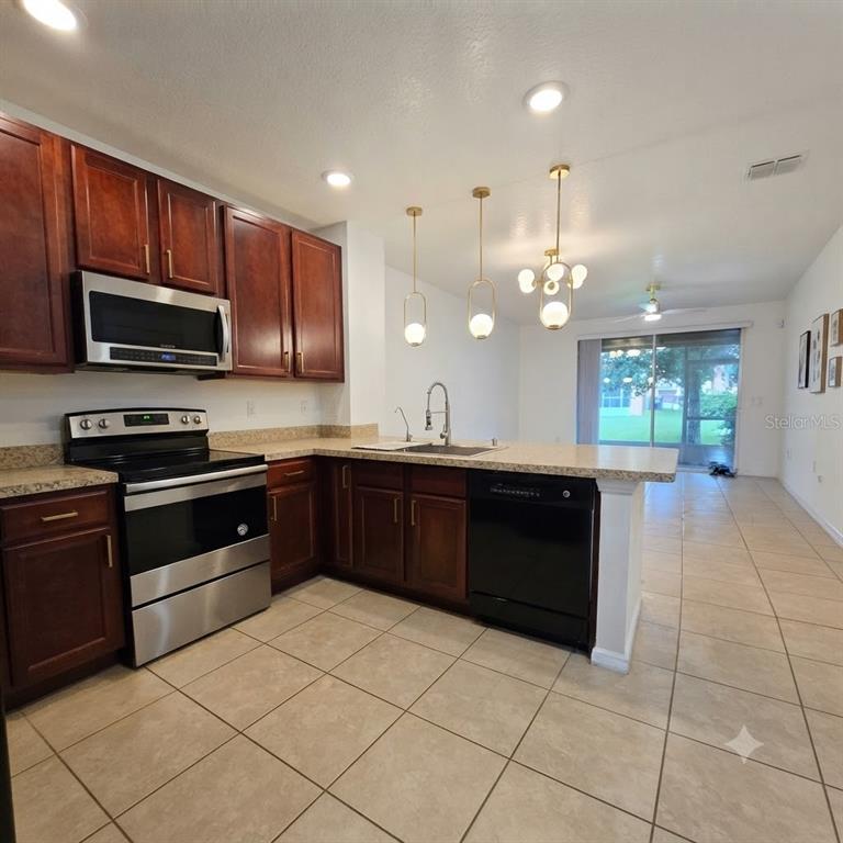 A kitchen with dark wood cabinets, stainless steel appliances, and a tile floor — 1561 CHELSEA DRIVE, DAVENPORT, FL