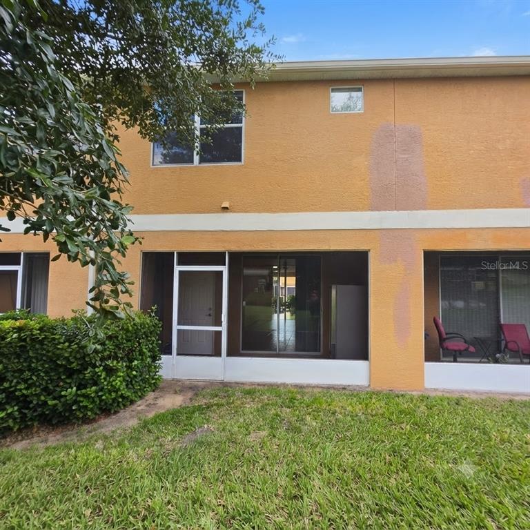 The exterior of a two-story townhouse features a screened-in patio and a grassy backyard — 1561 CHELSEA DRIVE, DAVENPORT, FL