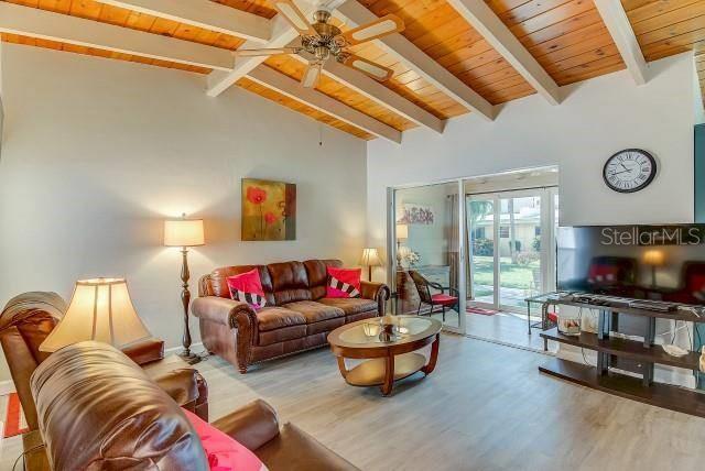 A living room features a brown leather sofa, wood-beamed ceiling, and a sliding glass door — 6006 MIDNIGHT PASS ROAD UNIT 24, SARASOTA, FL