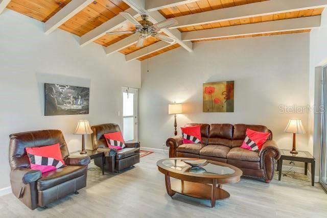 A living room features a brown leather sofa and armchair under a wood-beamed ceiling — 6006 MIDNIGHT PASS ROAD UNIT 24, SARASOTA, FL