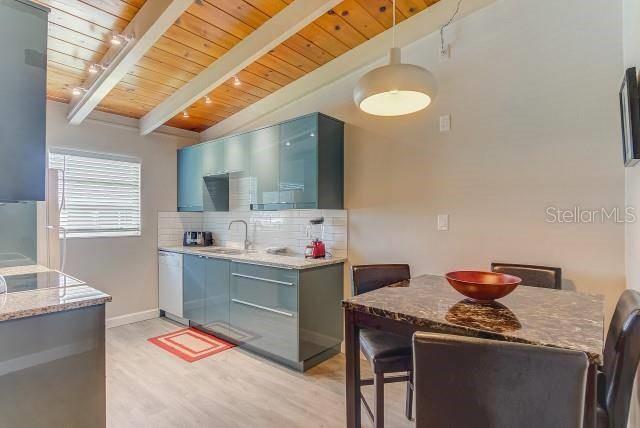 A kitchen with glossy blue cabinets, a marble-topped dining table, and a wood-paneled vaulted ceiling — 6006 MIDNIGHT PASS ROAD UNIT 24, SARASOTA, FL