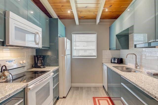 A modern kitchen features blue cabinets, stainless steel appliances, and a wood-paneled ceiling — 6006 MIDNIGHT PASS ROAD UNIT 24, SARASOTA, FL