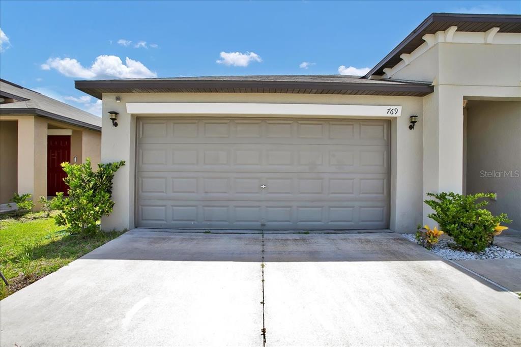 The exterior of a house features a beige garage door and a concrete driveway — 769 CALICO SCALLOP STREET, RUSKIN, FL