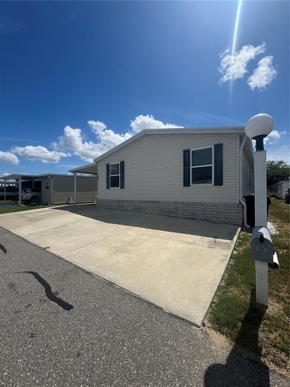 A light-colored mobile home with a concrete driveway and a mailbox on a post — 106 REINEKE ROAD, HAINES CITY, FL