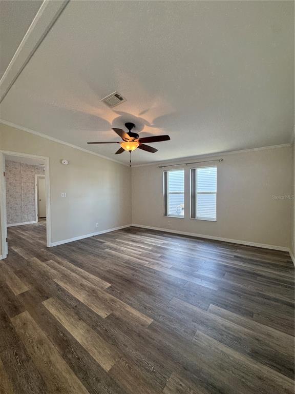 An empty living room features light-colored walls, wood-look flooring, and a ceiling fan — 106 REINEKE ROAD, HAINES CITY, FL