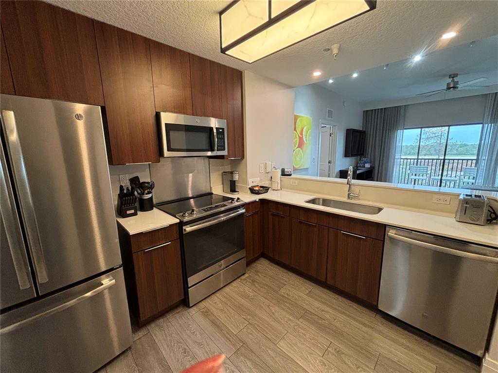 A modern kitchen features stainless steel appliances, dark wood cabinets, and light countertops — 14501 GROVE RESORT AVENUE UNIT 2532, WINTER GARDEN, FL