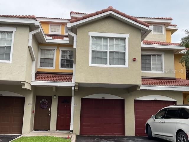 A multi-story townhouse exterior with tan stucco walls, red tile roofs, and two garage doors — 5711 BENTGRASS DRIVE UNIT 19-211, SARASOTA, FL