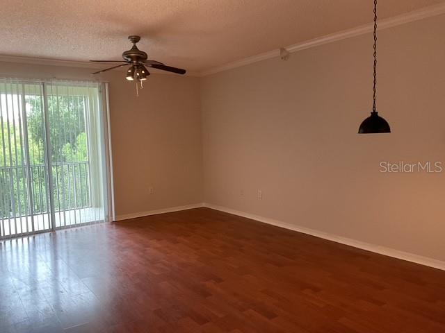 An empty room features wood-look flooring, a ceiling fan, and a sliding glass door — 5711 BENTGRASS DRIVE UNIT 19-211, SARASOTA, FL