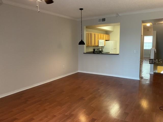 An open living area with wood-look flooring features a pass-through window into the kitchen — 5711 BENTGRASS DRIVE UNIT 19-211, SARASOTA, FL