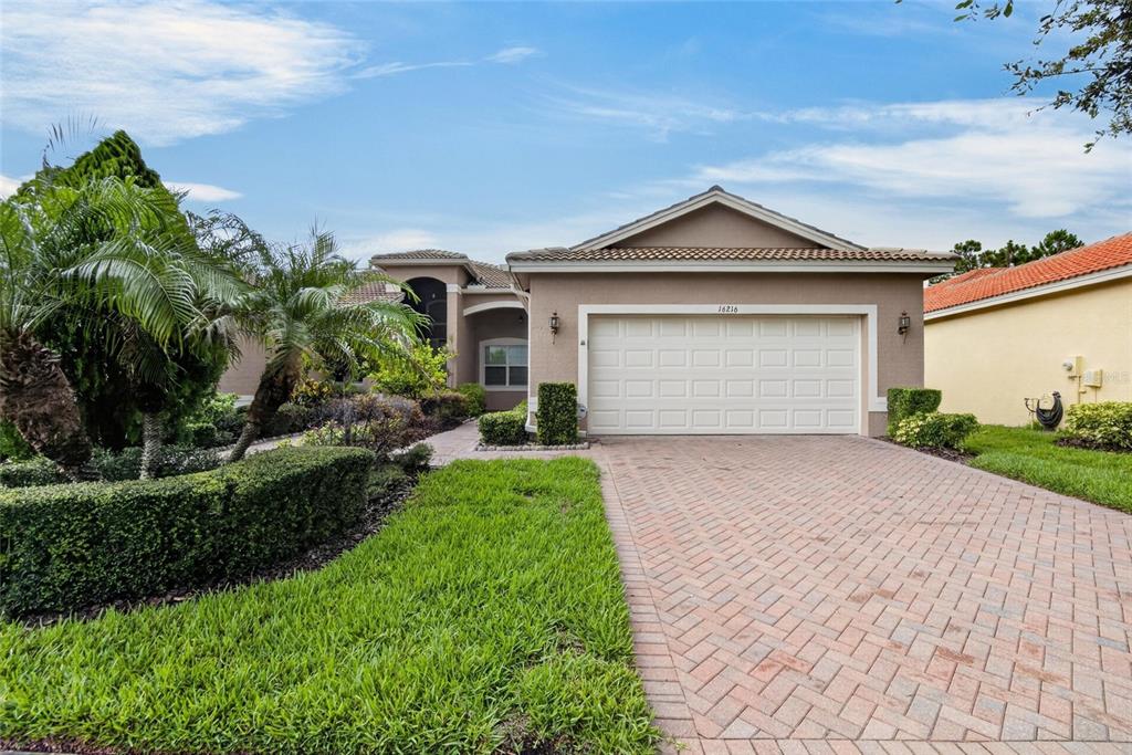 A single-story house with a beige stucco exterior, a two-car garage, and a paved driveway — 16216 AMETHYST KEY DRIVE, WIMAUMA, FL