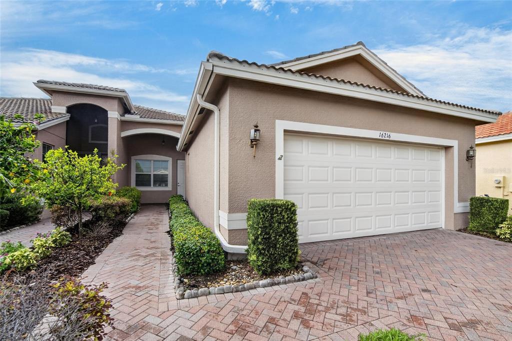 A tan house with a white garage door and a brick paver driveway — 16216 AMETHYST KEY DRIVE, WIMAUMA, FL
