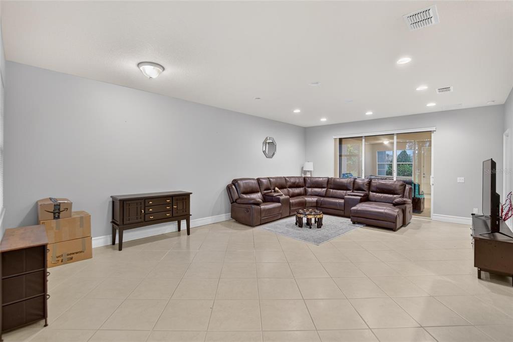 A spacious living room features light tile floors, gray walls, and a large brown sectional sofa — 16216 AMETHYST KEY DRIVE, WIMAUMA, FL