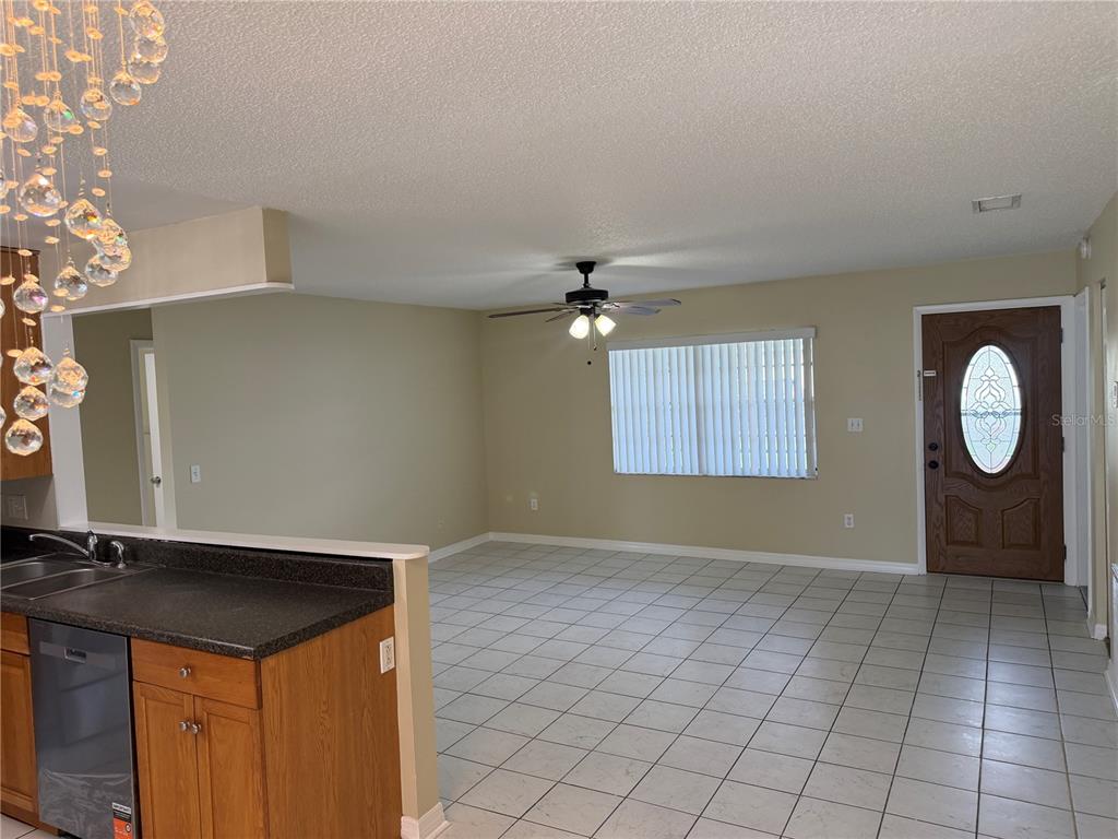 An open-concept living area features light-colored tile flooring, a ceiling fan, and a front door — 1069 BRIDLEWOOD WAY, BRANDON, FL