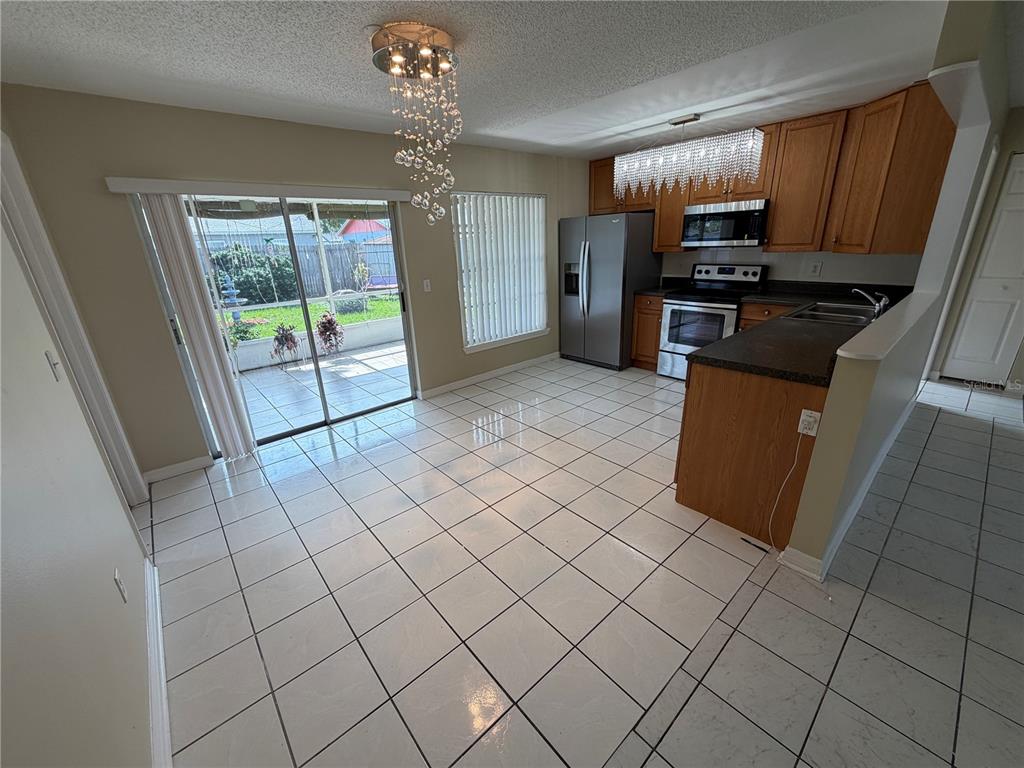 A kitchen and dining area with tile floors, wooden cabinets, and a crystal chandelier — 1069 BRIDLEWOOD WAY, BRANDON, FL