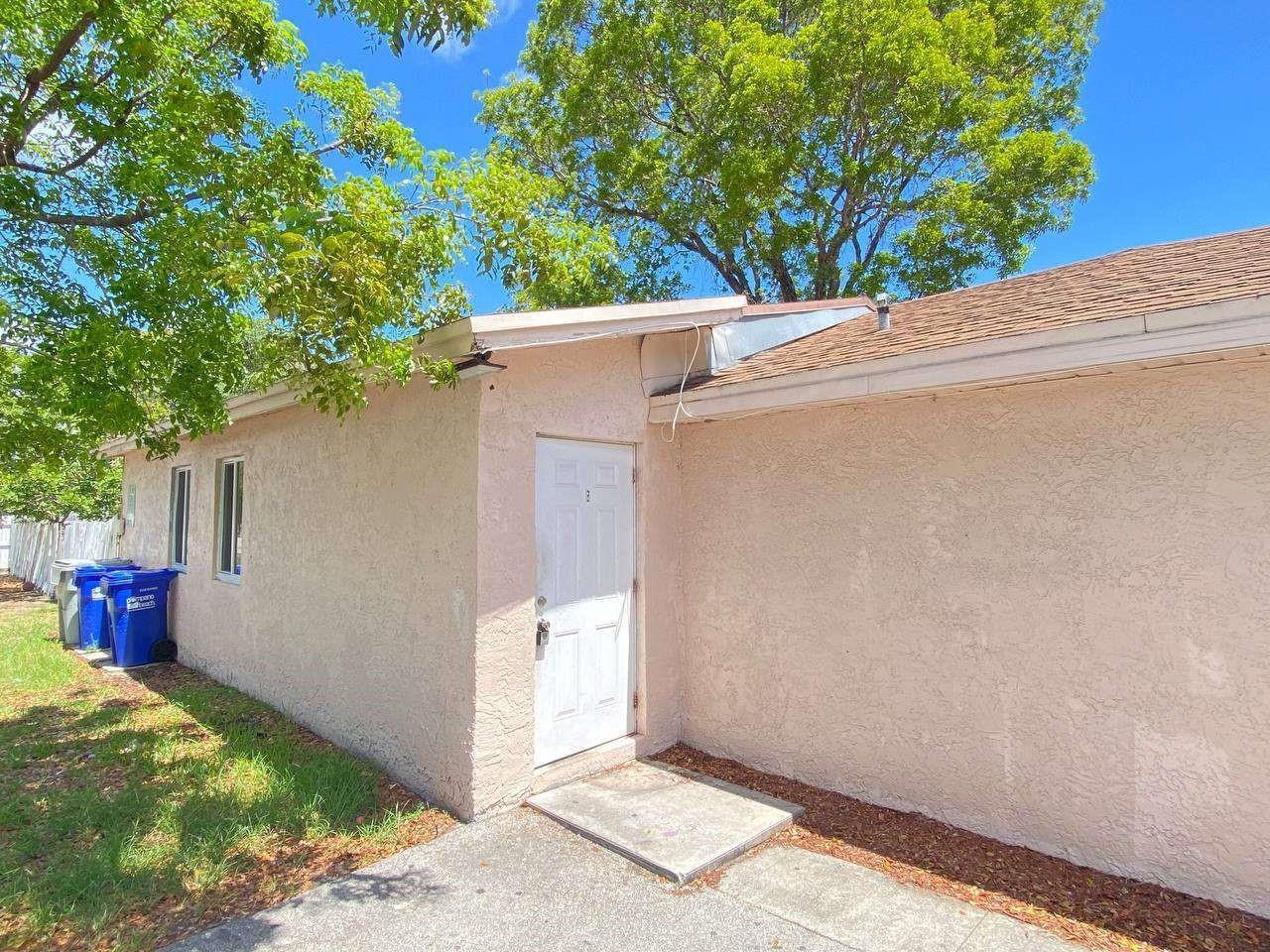 A side view of a stucco house exterior featuring a white door and two windows — 141 NW 10th Street, Pompano Beach FL 33060, POMPANO BEACH, FL