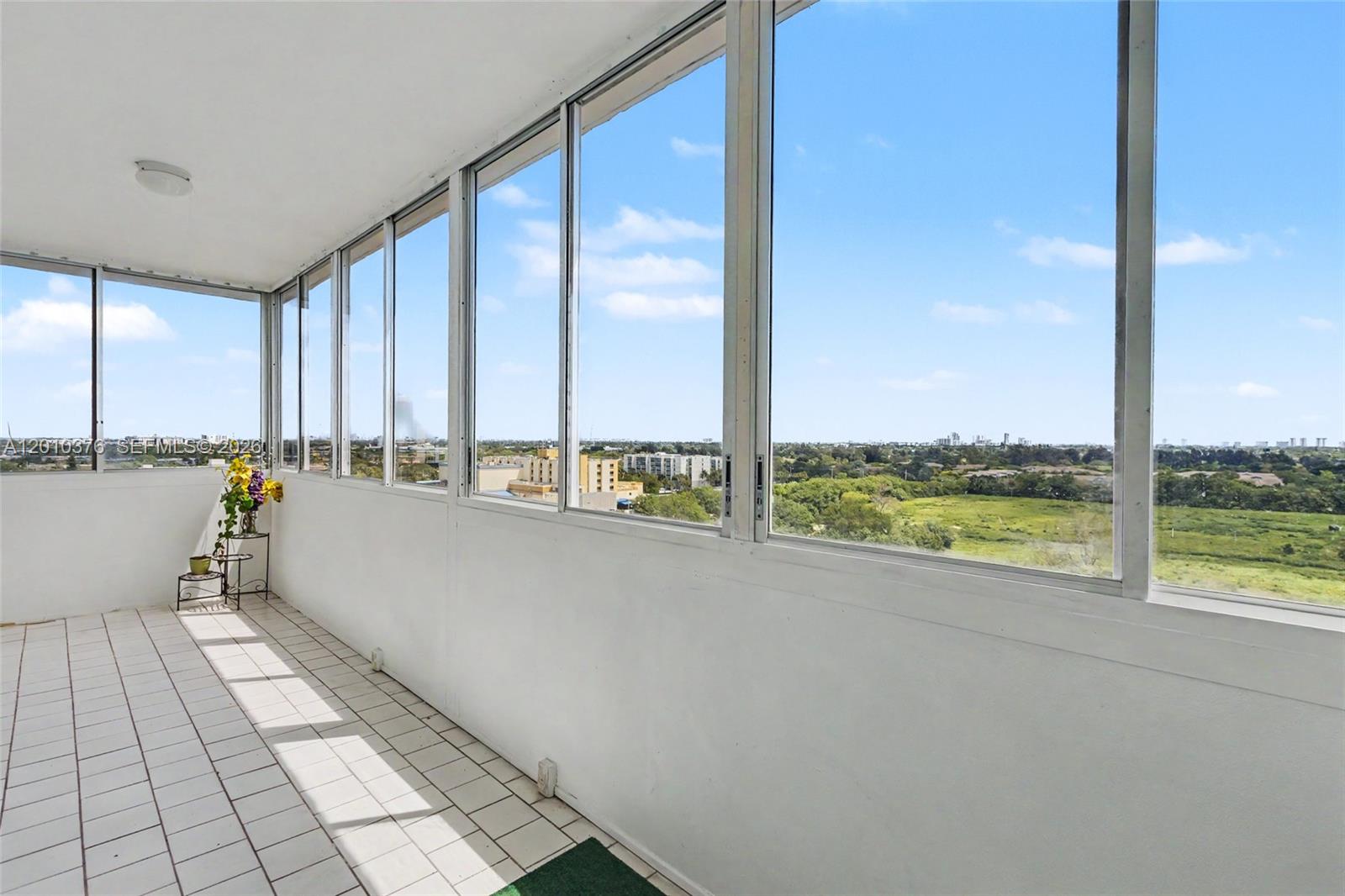 A sunroom with white tile flooring, white walls, and large windows overlooking a green landscape — 3800 Hillcrest Dr # 1211, Hollywood FL 33021, HOLLYWOOD, FL