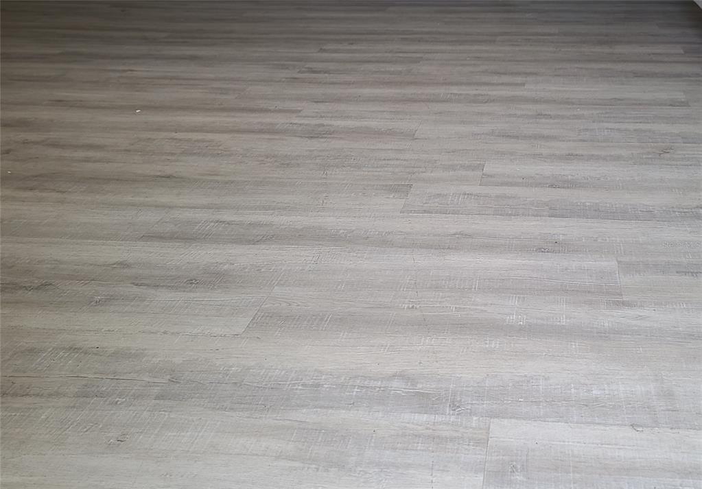 A close-up view of light gray wood-look laminate flooring planks — 101 LAKE AVENUE NE UNIT 222, LARGO, FL