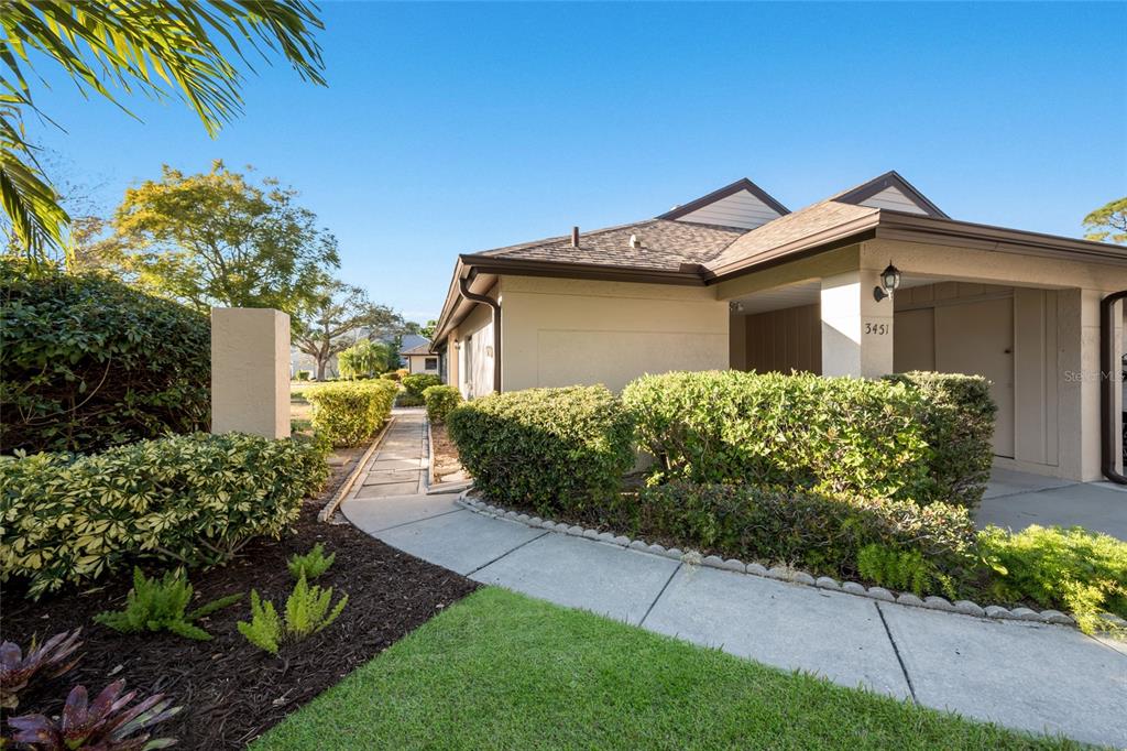 A concrete walkway leads to the entrance of a single-story home with manicured landscaping — 3451 51ST AVENUE CIRCLE W, BRADENTON, FL