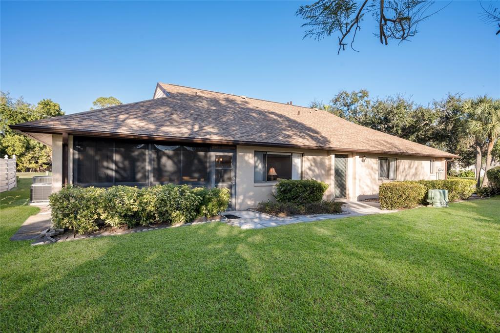 A single-story house with a screened-in porch, tan siding, and a large grassy yard — 3451 51ST AVENUE CIRCLE W, BRADENTON, FL