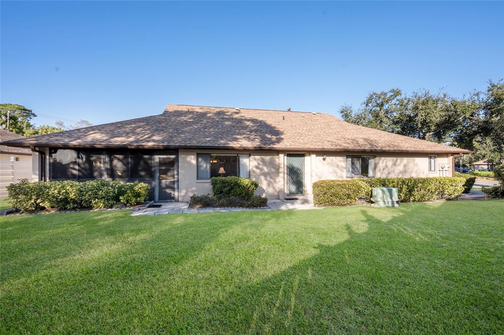 The exterior of a single-story house features a screened-in porch and a grassy lawn — 3451 51ST AVENUE CIRCLE W, BRADENTON, FL