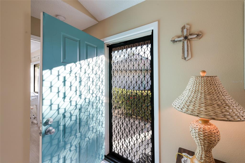 An open teal front door with a security screen leads into a home interior — 3451 51ST AVENUE CIRCLE W, BRADENTON, FL