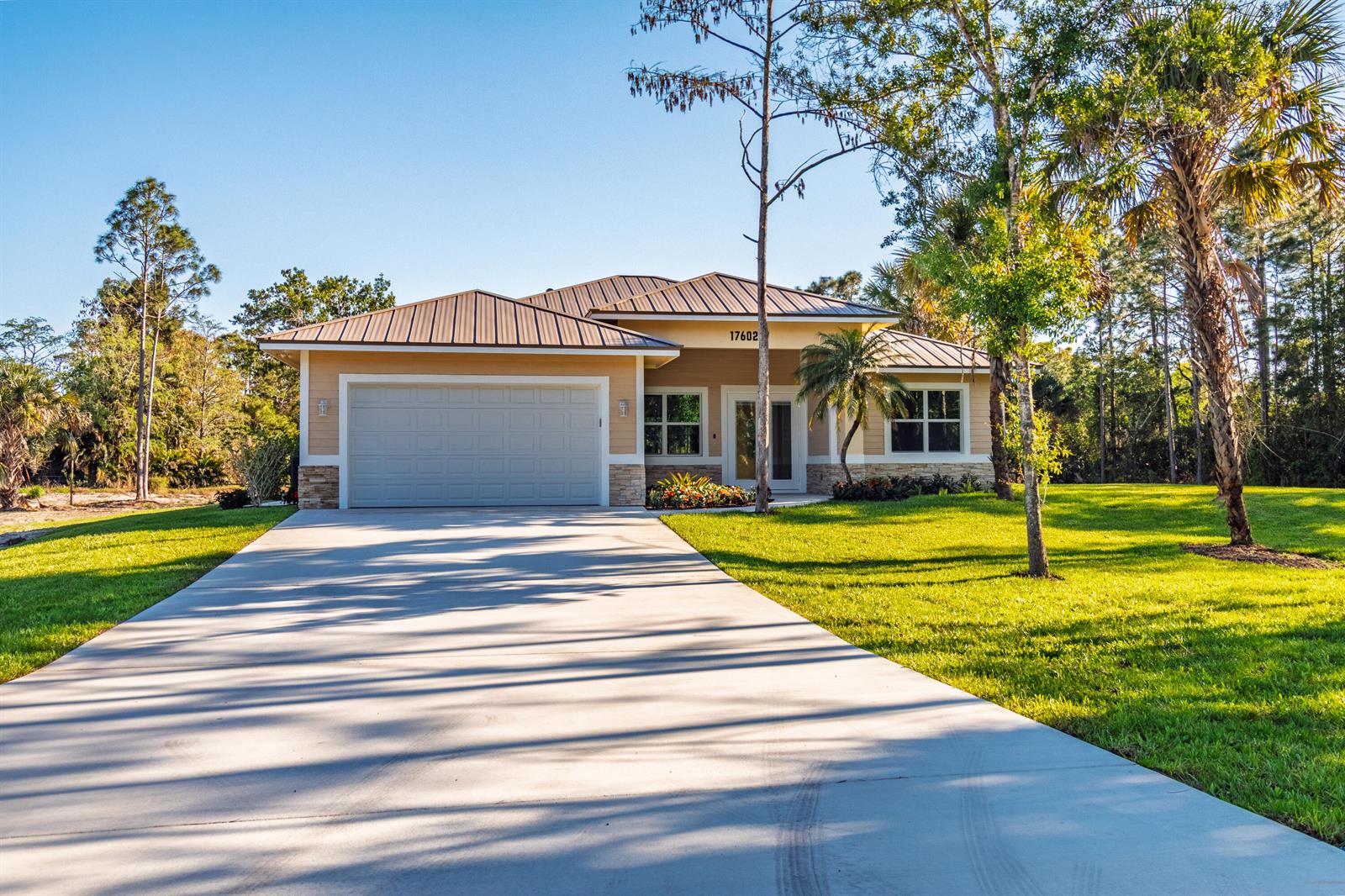 A single-story house with a tan exterior, metal roof, and a concrete driveway — 17602 63rd N, FL 33470, FL