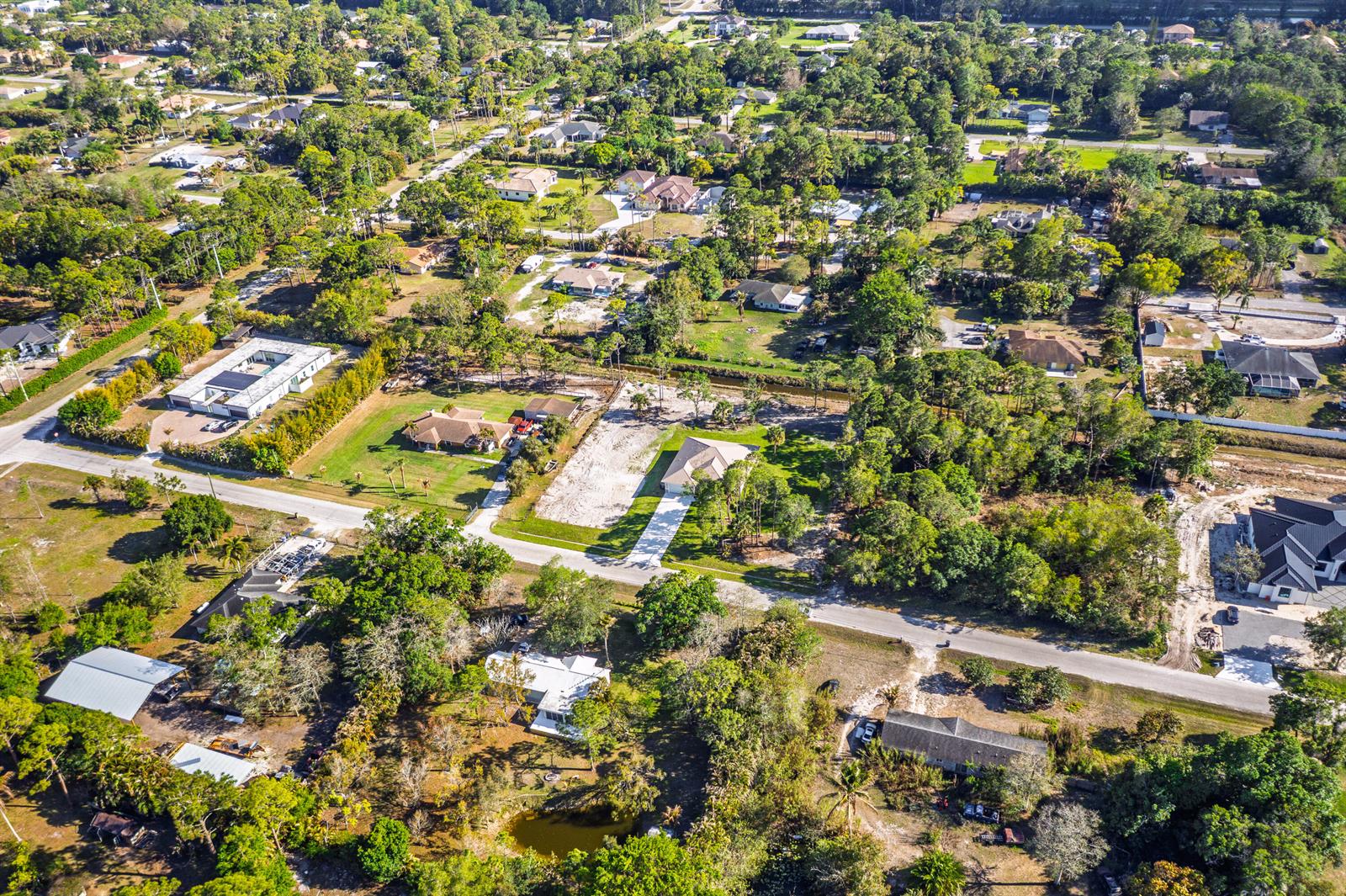 An aerial view shows several single-family homes surrounded by dense trees and vacant lots — 17602 63rd N, FL 33470, FL