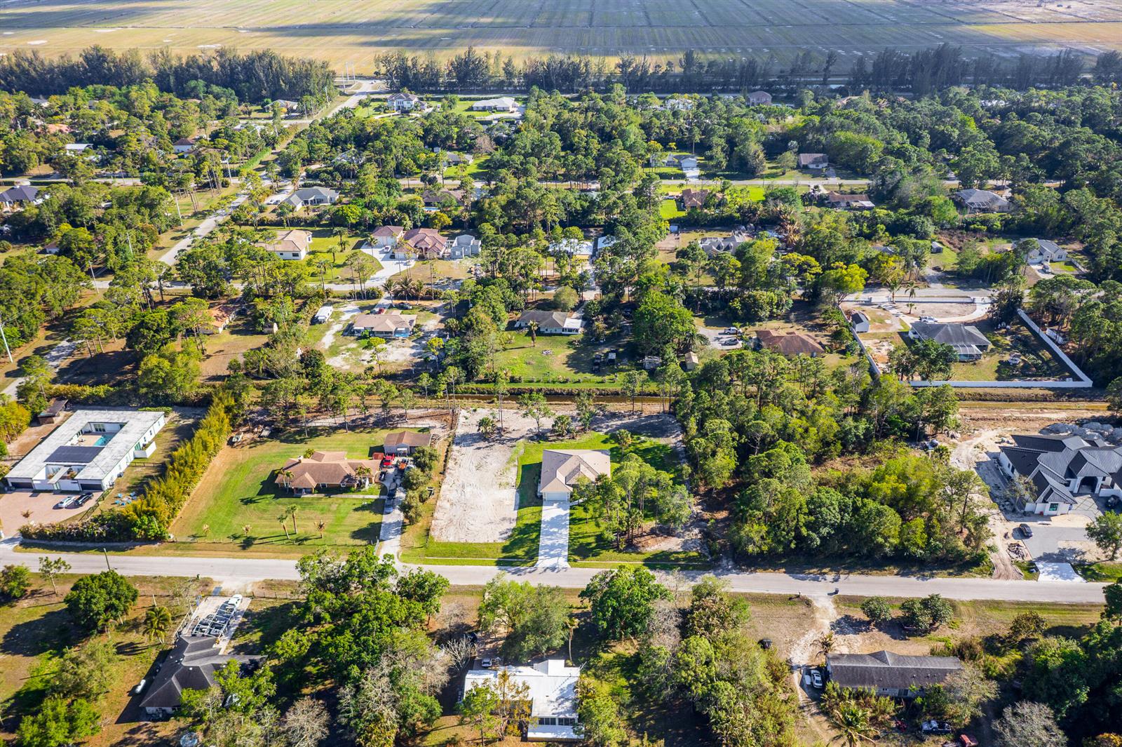 An aerial view shows a residential neighborhood with single-family homes, wooded lots, and paved roads — 17602 63rd N, FL 33470, FL
