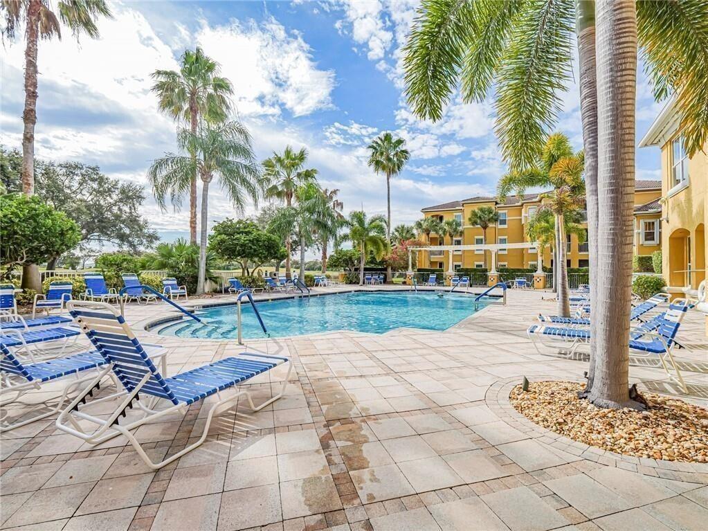 A swimming pool surrounded by lounge chairs, palm trees, and a multi-story apartment building — 5095 Fairways Circle # I303, Vero Beach FL 32967, VERO BEACH, FL