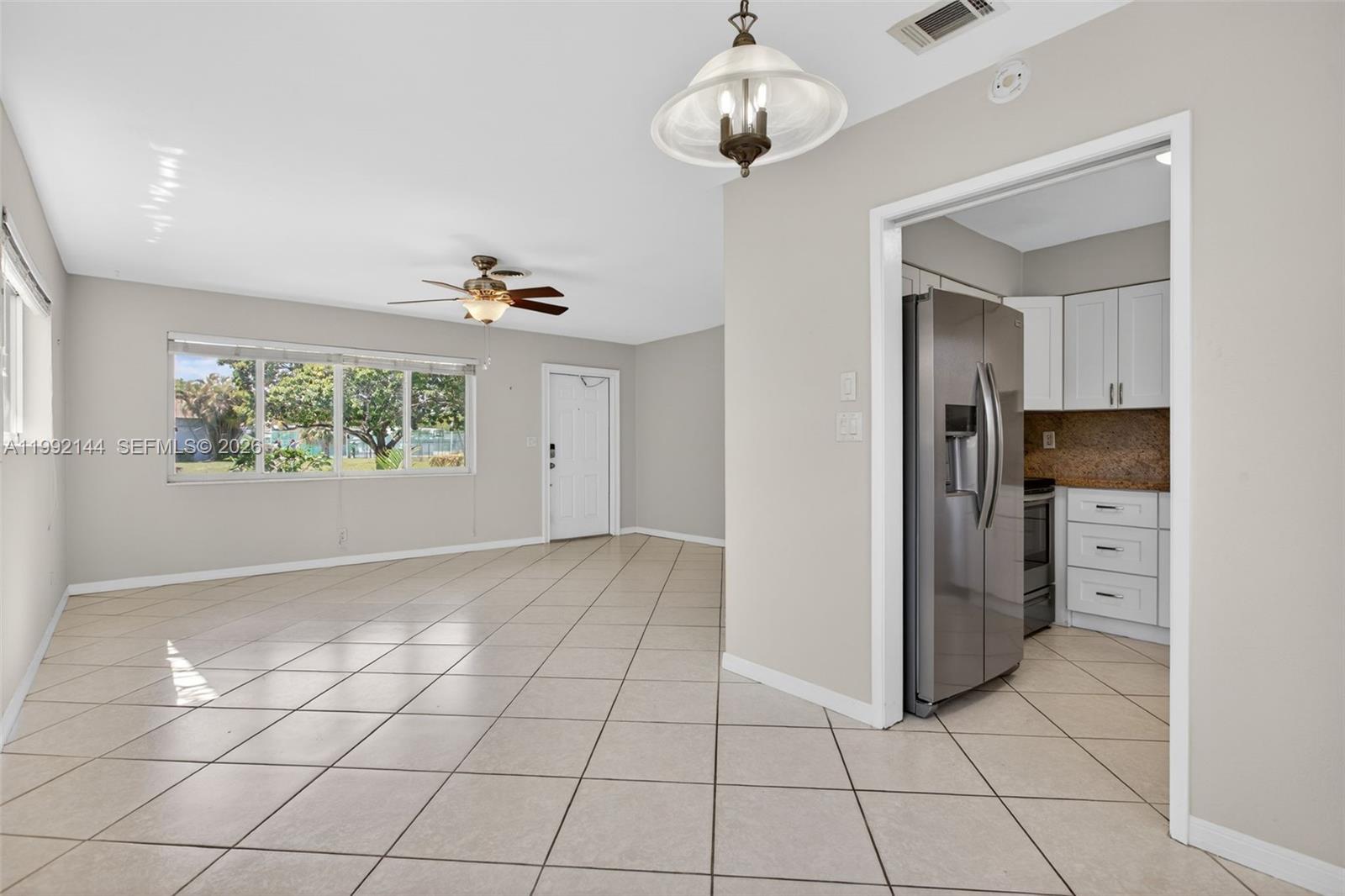 An open-concept living area with tile floors leads into a kitchen with white cabinets — 3900 NE 22nd Ave, Lighthouse Point FL 33064, LIGHTHOUSE POINT, FL