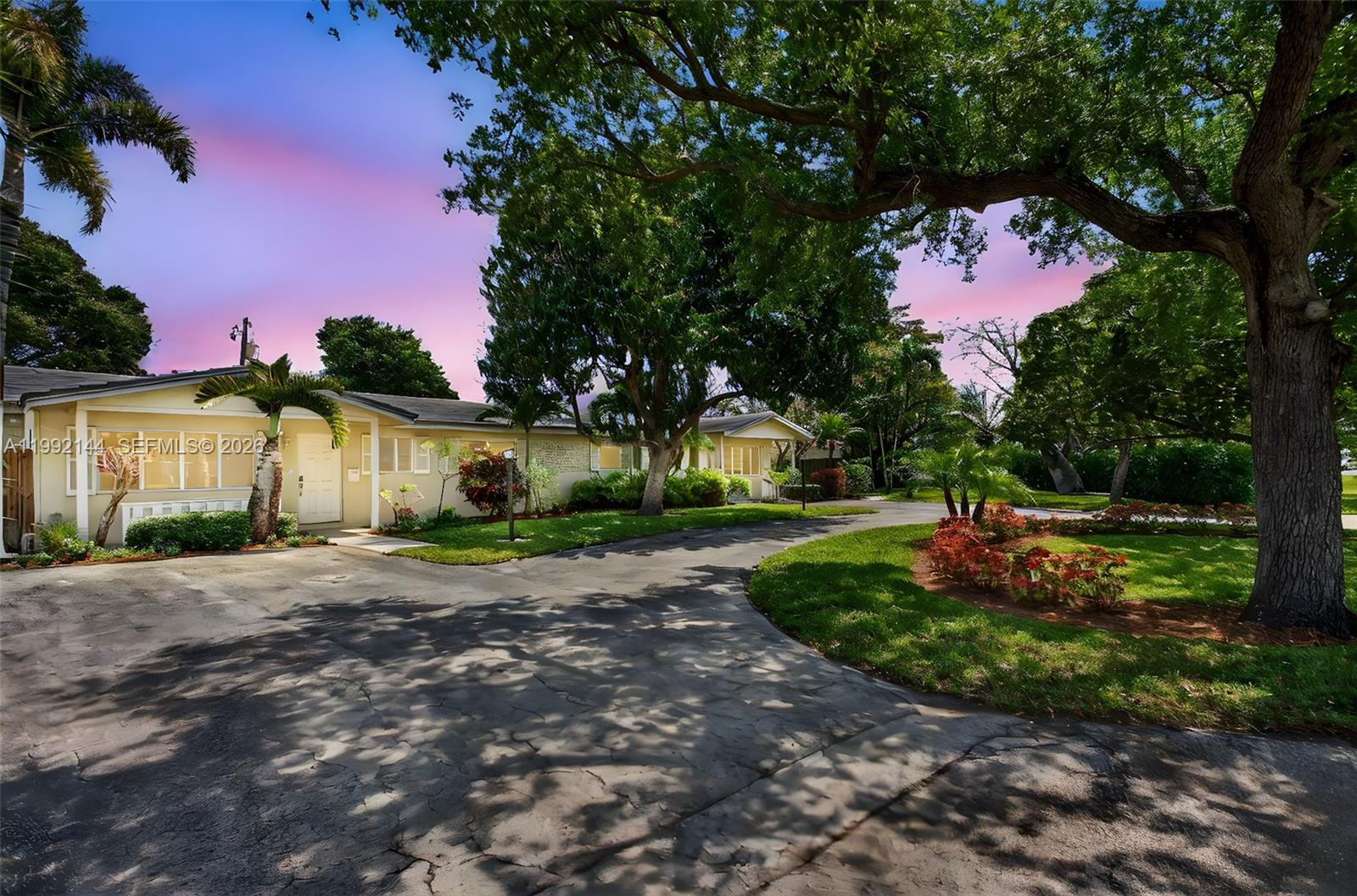 A single-story house with a curved driveway and large trees under a sunset sky — 3900 NE 22nd Ave, Lighthouse Point FL 33064, LIGHTHOUSE POINT, FL