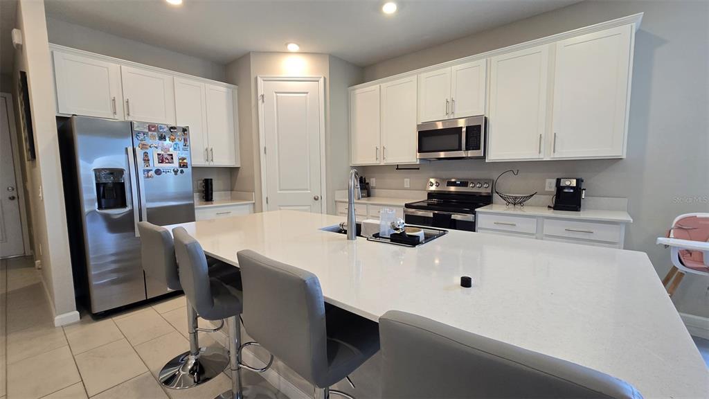 A kitchen features white cabinets, stainless steel appliances, and a large central island with seating — 802 BALLANTYNE DRIVE, LAKE WALES, FL