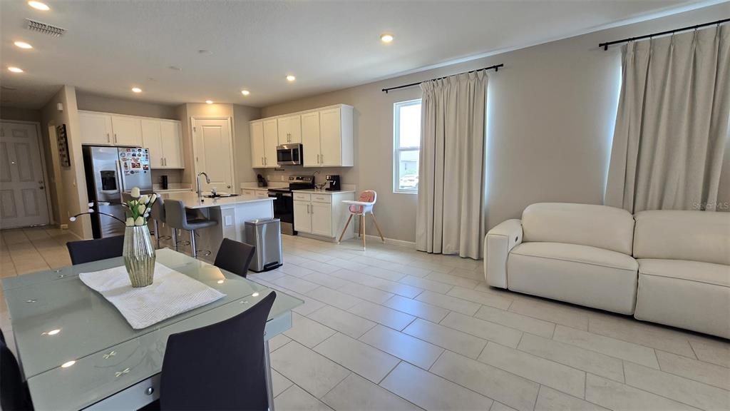 An open-concept kitchen and dining area features white cabinetry, a central island, and tile flooring — 802 BALLANTYNE DRIVE, LAKE WALES, FL