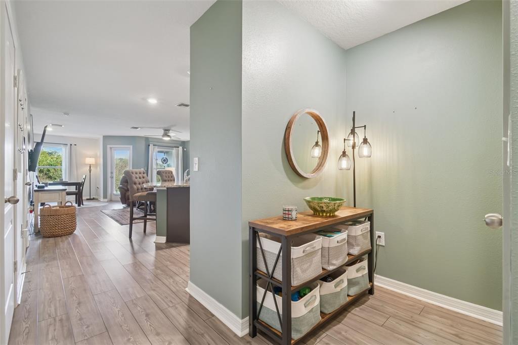 An entryway with a wooden console table and storage baskets leads into an open living area — 5228 NEW FRIENDSHIP PLACE, TAMPA, FL