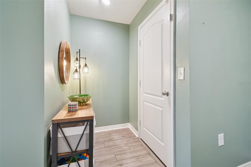 A hallway features light green walls, wood-look flooring, a console table, and a white door — 5228 NEW FRIENDSHIP PLACE, TAMPA, FL