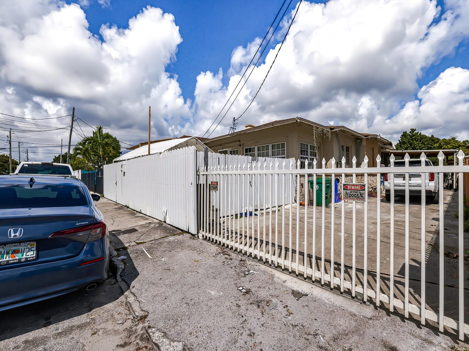 A white metal fence encloses a driveway in front of a single-story house — 1757 NW 1st Street, Miami FL 33125, MIAMI, FL