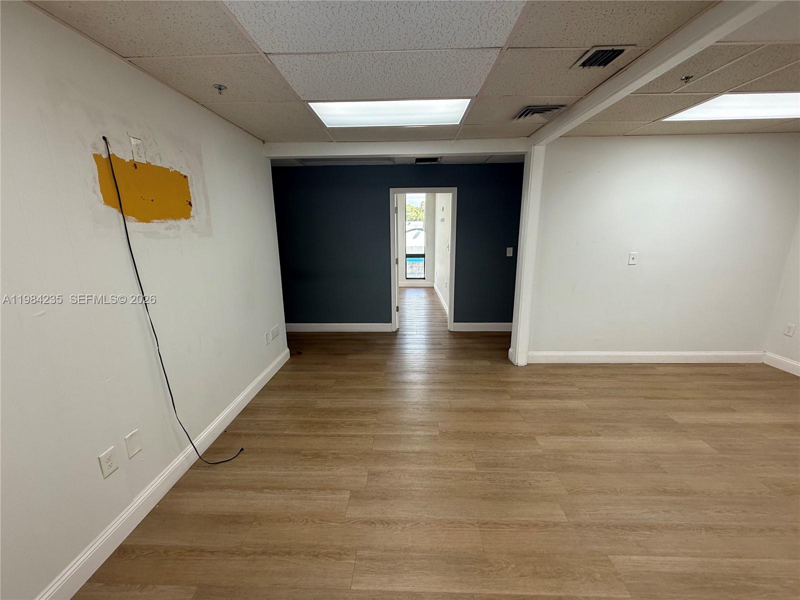 An empty office space features wood-look flooring, white walls, and a dark blue accent wall — 810 NE 125th St, North Miami FL 33161, NORTH MIAMI, FL